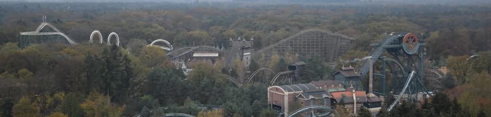 The park seen from above in autumn, with several roller coasters rising out of dense woodland that runs to the horizon.