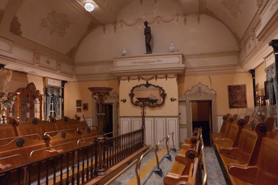 The ornate panelled interior of the Villa Volta ride, with rows of wooden benches under a vaulted ceiling.