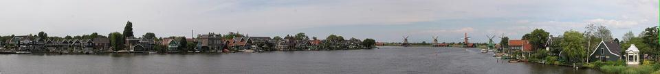 Wide view across the river Zaan, with historic houses along one bank and the row of windmills on the other.