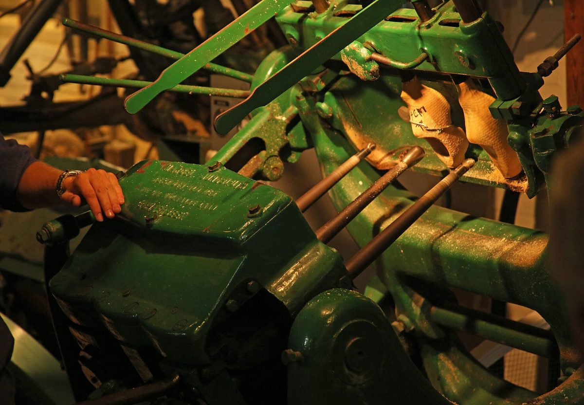 Een klomp wordt gevormd op een traditionele groene kopieerbank in de klompenmakerij.