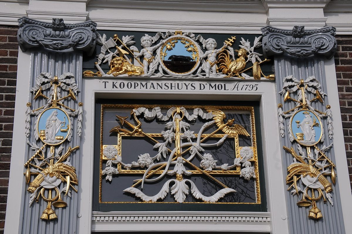 Rijk verguld en beschilderd snijwerk boven de deur van een koopmanshuis uit 1795.